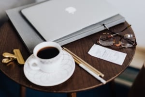 Cozy workspace with coffee, laptop, and glasses, embodying a modern home office atmosphere for Portland real estate buyers.