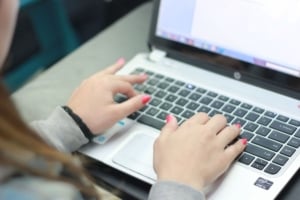 Hands typing on a laptop, researching Portland real estate listings and home features for informed property investment decisions.