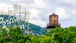 Portland Oregon sign with leaping deer and Old Town water tower framed by green trees