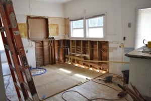 Kitchen under renovation with exposed wall studs, wiring, and tools on the floor