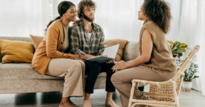 Young couple meeting with real estate agent at home to discuss buying or selling options