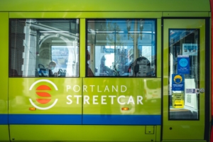 The side of a brightly colored Portland Stgreetcar going through downtown Portland.