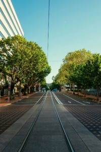 Train tracks running through the streets Portland Oregon on a tree lined street.