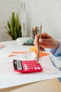 Calculating budgets and expenses for residential real estate investments with a calculator and paperwork on a desk.