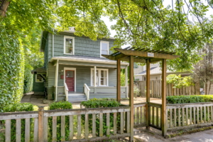 Charming green single-family home for rent featuring inviting porch, landscaped yard, and modern curb appeal for Portland real estate.