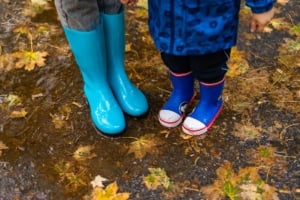 Children wearing colorful rain boots, enjoying a rainy day outdoors, showcasing delightful family-friendly living in Portland.
