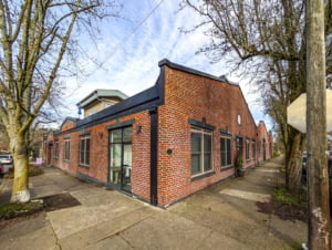 Converted industrial building in Portland showcasing modern residential potential with unique brick façade and large windows.