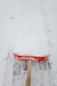 Shoveling snow from a residential driveway, showcasing winter home maintenance for Portland homeowners and real estate enthusiasts.