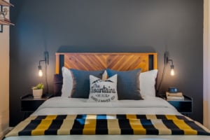Cozy primary suite featuring a rustic wood headboard, modern lighting, and stylish decor, ideal for Portland homeowners.