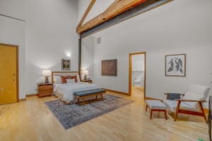 Spacious primary suite featuring vaulted ceilings, warm wood accents, and modern furnishings in a Portland residence.