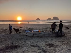 Family enjoying a beach sunset, ideal for lifestyle in coastal Portland real estate, showcasing outdoor gatherings and pets.