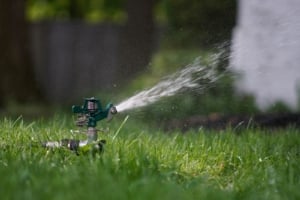 Lush green lawn irrigated by a sprinkler, enhancing curb appeal for Portland single-family homes and investment properties.