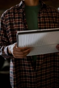 Man holding an air filter, representing home maintenance for healthy living in Portland real estate. Essential for residential upkeep.