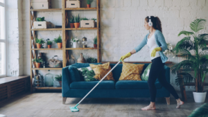 Woman cleaning a stylish open-concept living space with a modern couch and greenery, showcasing Portland's residential lifestyle.